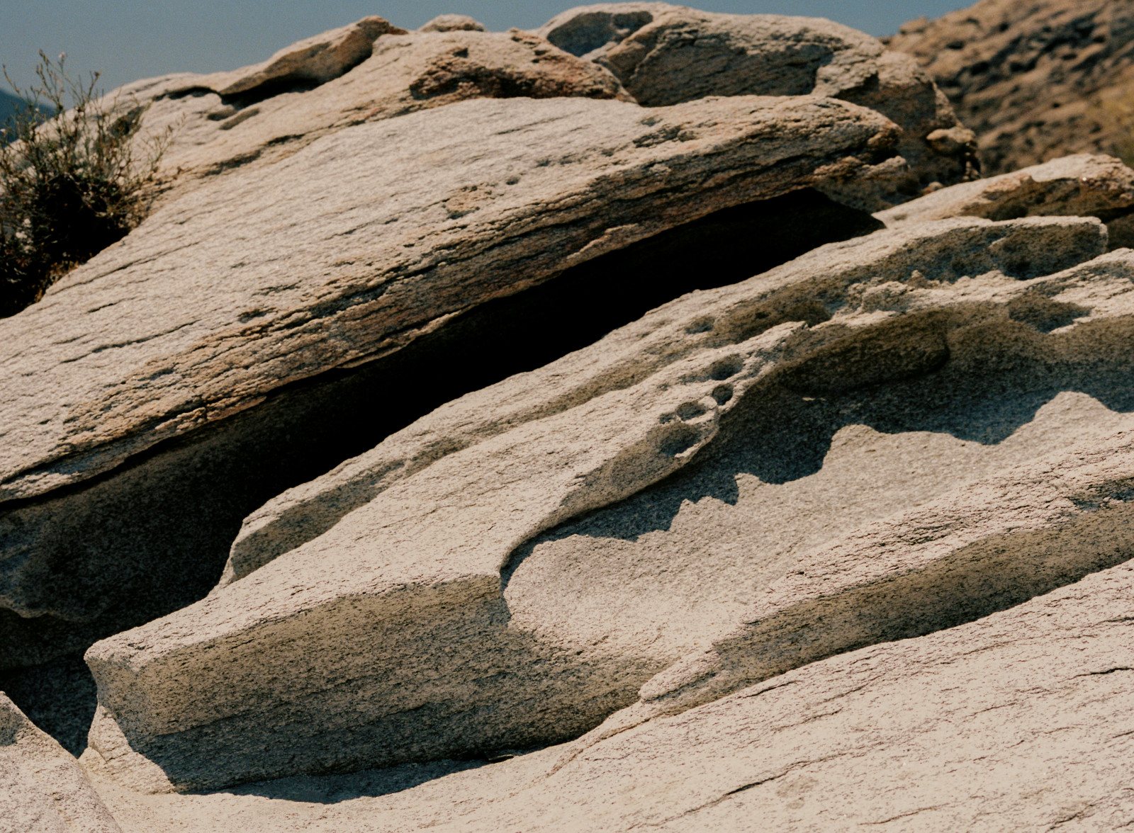 Slabs of sand-coloured stone overlap, with a deep shadowed gap between them.